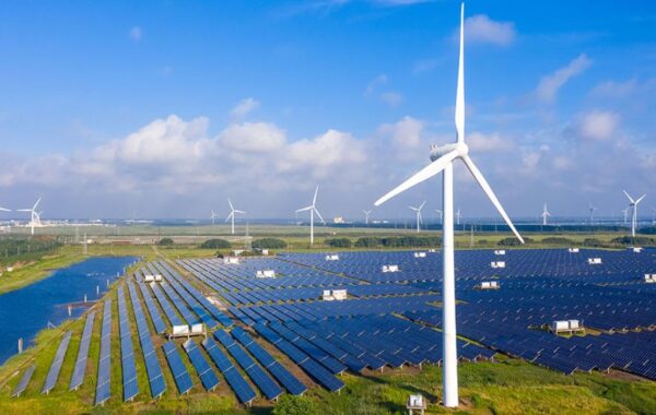 l'immagine riporta un campo fotovoltaico con molti pannelli e delle pale eoliche, no petrolio